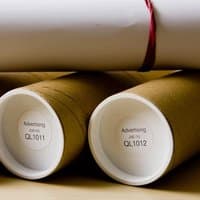 Brother DK11218 round labels, 24mm, white with black text, on brown cardboard rolls with white end caps.