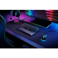 Black Razer wrist rest with leather surface and memory foam, placed in front of a keyboard on a gaming desk.