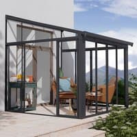 Grey lean-to conservatory with clear panels, metal frame, and sliding doors, attached to a white wall.