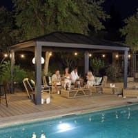 Grey metal garden gazebo with flat roof, open sides, and sturdy frame, set on a wooden deck by a pool.
