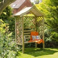 Wooden garden arbour seat with lattice sides, curved roof, and bench, surrounded by greenery.