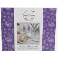 Bee and Bumble Pottery Starter Kit with pastel paints, brushes, and clay, in a purple floral-patterned box.