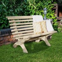 Curved wooden garden bench with slatted backrest and seat, light brown finish, set on green grass near a brick wall.