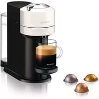 White Nespresso Vertuo Next coffee machine with black base, clear water tank, and three coffee capsules nearby.