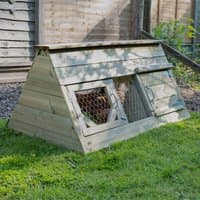 Wooden A-frame chicken coop with mesh windows and hinged doors on grassy area.
