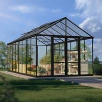 Black polycarbonate greenhouse with clear panels, peaked roof, and spacious interior, surrounded by greenery.