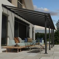 Grey Palram Canopia patio cover with clear panels, sleek metal frame, attached to house over outdoor seating area.