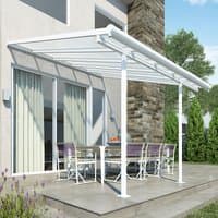 White 10x10 Palram Canopia Sierra patio cover with clear roof panels and white frame over outdoor dining area.