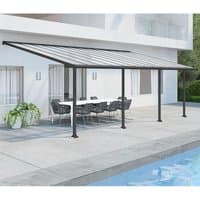 Grey Palram Canopia patio cover with clear panels, supported by black posts, over a patio with outdoor furniture.