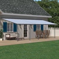 Grey Palram Canopia Sierra patio cover with clear roof panels and aluminum frame attached to house over wooden deck.
