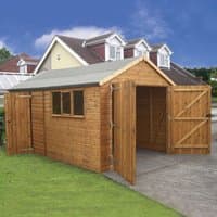 Wooden garage shed with shiplap cladding, double doors, side window, pitched roof, set on concrete driveway.