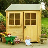 Wooden garden playhouse with green roof, two square windows, and a single door, surrounded by toys and plants.