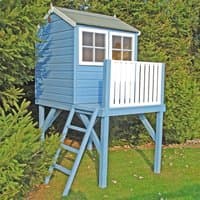 Blue wooden children's playhouse with white railings, windows, and ladder on a raised platform in a garden setting.