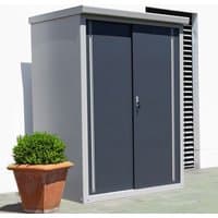 Trimetals Guardian D43 metal storage shed, gray with dark sliding doors, flat roof, next to a potted plant.