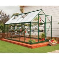 Green Palram Canopia greenhouse with clear polycarbonate panels and green frame, set on a wooden base.