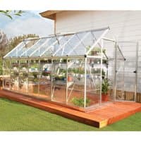 Silver polycarbonate greenhouse with clear panels, pitched roof, and aluminum frame on wooden deck.