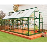 Green Palram Canopia greenhouse with clear polycarbonate panels and green metal frame on wooden deck.