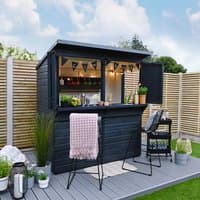Black shiplap garden bar with open hatch, wooden counter, bunting, and potted plants on a decked area.