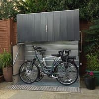 Anthracite metal bike shed with ramp, vertical panel design, and secure lock, housing two bicycles.