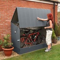 Anthracite metal bike shed with sloped roof, ramped base, and front-opening lid, housing two bicycles.