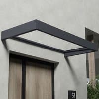Grey Palram Canopia door canopy with clear roof, rectangular frame, mounted above a wooden door on a concrete wall.