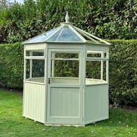 Octagonal painted wooden greenhouse in pale green with glass roof panels and a pointed finial.