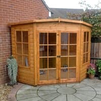 Wooden Shire Hampton garden summerhouse with double glass doors and windows, set on a circular patio.