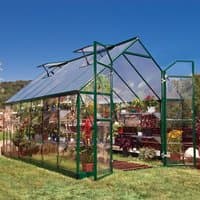 Green metal-framed greenhouse with clear panels, featuring a peaked roof and open vents, set on grass.