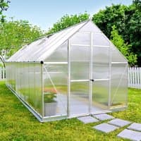 Aluminium-framed greenhouse with clear panels, pitched roof, and double doors, set on grass with a white fence nearby.