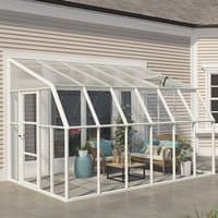 White-framed 8x12 Palram Canopia Rion sunroom with clear panels attached to house, featuring a sloped roof.