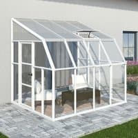 White-framed 8x8 Palram Canopia Rion sunroom with clear panels, sloped roof, and door, set on a stone patio.