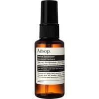 Amber bottle of Aesop Herbal Deodorant Spray with black pump and white label detailing ingredients.