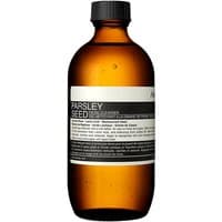 Amber bottle of Aesop Parsley Seed Facial Cleanser, black cap, white label with black text, 200 ml.