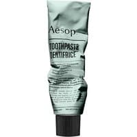 Aesop toothpaste in a crumpled metallic tube with black cap and minimalist black text design.