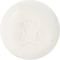 Round white soap with embossed Creed logo and text, "Green Irish Tweed Savon 150 g," elegant and minimalist design.