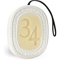 Cream oval scented disc with embossed "34" and black hanging cord, by Diptyque.