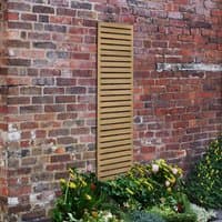 Wooden slatted trellis panel, 6' x 1', pressure-treated, vertical slats, mounted on a brick wall with flowers below.
