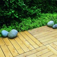 Forest Patio Deck Tile 90cm, pack of 4, light wood slats with interlocking edges, set on a green garden background.