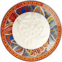 White Fragonard soap with floral design on colorful patterned soap dish.