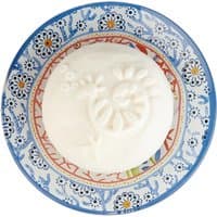 White Fragonard soap with floral imprint on a blue and red patterned ceramic soap dish.