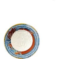 Round white soap on a colorful ceramic dish with blue, red, and brown floral patterns.