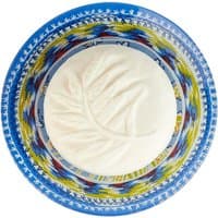 Round white soap with leaf imprint in a colorful blue, yellow, and red patterned soap dish.