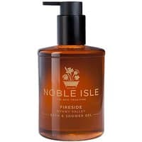 Amber bottle of Noble Isle Fireside Bath & Shower Gel with black pump and white floral logo.