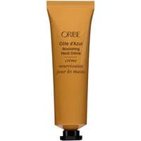 Gold tube of Oribe Cote d'Azur Nourishing Hand Cream, black cap, elegant text on front.