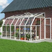 White Palram Canopia Rion sunroom with clear panels, attached to brick house, featuring plants and shelving inside.