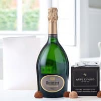 Ruinart Brut champagne bottle, 12 chocolate truffles, and a white occasion card on a light background.