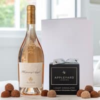 Whispering Angel Rosé bottle, black box of 12 truffles, white occasion card, set on a light background.